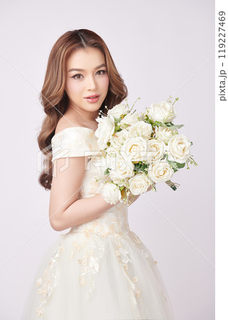Beautiful young asian woman in wedding dress holding bouquet on white background, 119227469
