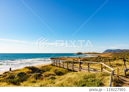 Woman walking on wooden path on sea shore 119227901