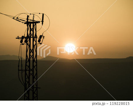 High voltage towers on coast at sunset High voltage towers on coast at sunset 119228015