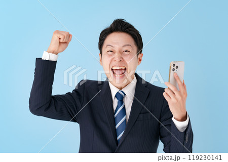 スマホを持ってガッツポーズをするビジネスマン 119230141