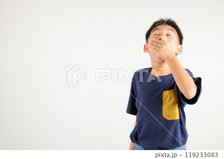 Portrait Asian young kid boy emotions tired and sleepy yawning covering mouth open by hand, studio shot isolated on white background, Thai primary child insomnia concept with copy space 119233083