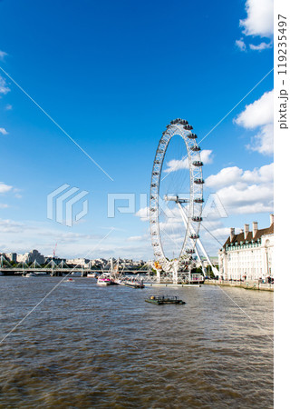 大きな雲が浮かぶ真っ青な空の下のロンドンアイと歴史的な建物　ロンドンのテームズ川脇の街並み 119235497