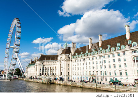 大きな雲が浮かぶ真っ青な空の下のロンドンアイと歴史的な建物　ロンドンのテームズ川脇の街並み 119235501