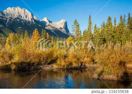 Beautiful scenery of the Canadian Rockies at dawn in autumn. Mountain, forest in yellow and green color reflected on water. Canmore, Alberta, Canada. Mount Lawrence Grassi. Beautiful scenery of the Canadian Rockies at dawn in autumn. Mountain, forest in yellow and green color reflected on water. Canmore, Alberta, Canada. Mount Lawrence Grassi. 119235636