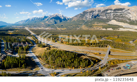 Aerial view of Trans-Canada Highway (Highway 1) exit 93 to Town of Canmore in Canadian Rockies in autumn sunny day. Alberta, Canada. Transportation concept. Aerial view of Trans-Canada Highway (Highway 1) exit 93 to Town of Canmore in Canadian Rockies in autumn sunny day. Alberta, Canada. Transportation concept. 119235648