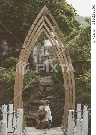 Vintage matte effect photo. Happy lifestyle moment. Man crouched, gesture hand, look into eyes each other listen boy walk funny play. Father hug hold child son closely arm embrace, fatherhood love 119238350