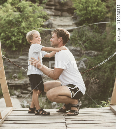 Vintage matte effect photo. Happy lifestyle moment. Man crouched, gesture hand, attentive listen boy walk funny play. Father hug hold touch child son closely in arms embrace, fatherhood love affection Vintage matte effect photo. Happy lifestyle moment. Man crouched, gesture hand, attentive listen boy walk funny play. Father hug hold touch child son closely in arms embrace, fatherhood love affection 119238351