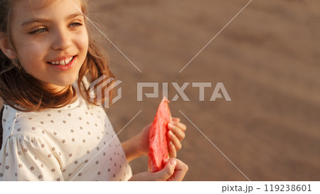 Happy smiling girl holds slice of ripe red watermelon in summer on beach 119238601