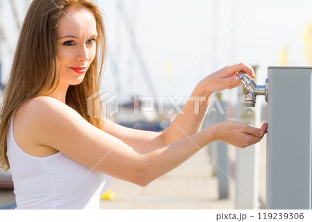 Woman drinking water from tap in marina. 119239306