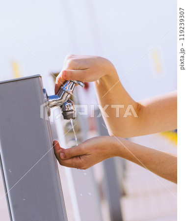Woman drinking water from street tap Woman drinking water from street tap 119239307