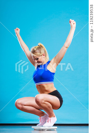 Joyful girl standing on weighing scale 119239538