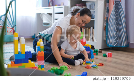 Cheerful mother and her baby share joyful moments while exploring colorful wooden toys in their nursery Cheerful mother and her baby share joyful moments while exploring colorful wooden toys in their nursery 119239709