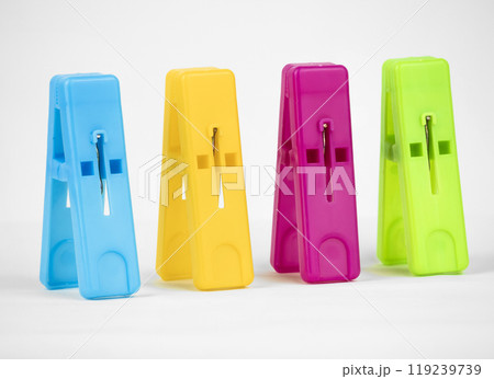 A collection of four colorful clothespins arranged neatly, showcasing vibrant blue, yellow, pink, and green shades against a clean white background 119239739
