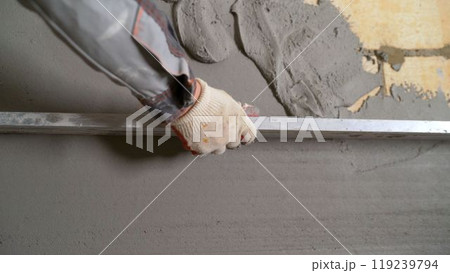 Construction worker leveling concrete mortar using aluminum straight edge 119239794