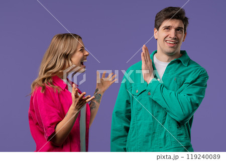 Grumpy woman quarrels on husband or boyfriend On violet. Tired man covers ears 119240089