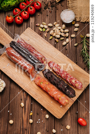 Assorted gourmet salami slices with nuts and spices on board, charcuterie and deli platters 119240669