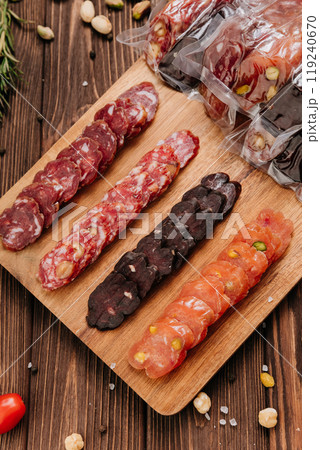 Assorted gourmet salami slices with nuts and spices on board, charcuterie and deli platters 119240670