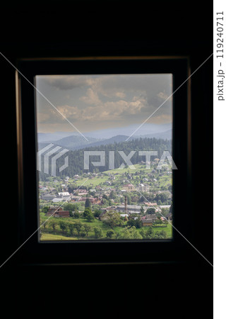 Vorokhta village view through window frame showcasing Carpathian mountains and green hills 119240711