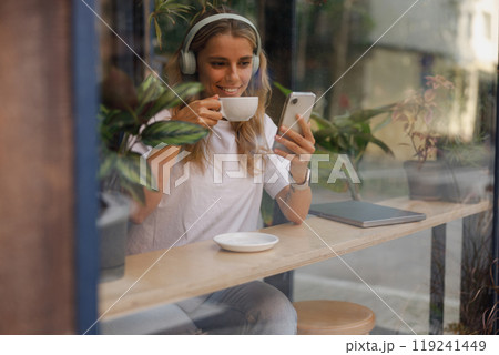 Woman Enjoying Coffee and Music in a Cozy Caf 119241449
