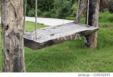 Wooden swing hanging on a rope in a park. 119242055