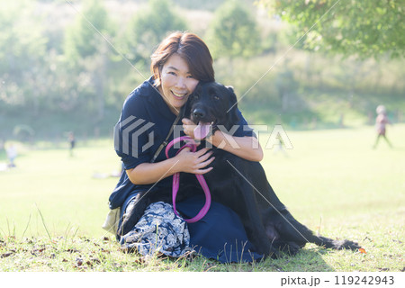 緑がきれいな場所でペットの大型犬と飼い主の女性　カメラ目線のクローズアップ　コピースペースあり 119242943