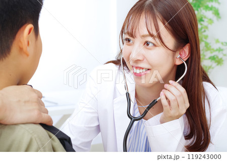 子どもの診察をする白衣の若い女性 119243000