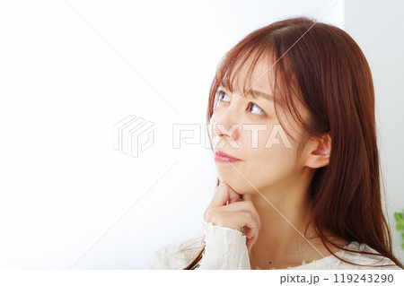 困り顔で考え事をしている若い女性 119243290