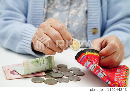 Asian senior or elderly old lady woman holding counting coin money in purse. Poverty, saving problem in retirement. Asian senior or elderly old lady woman holding counting coin money in purse. Poverty, saving problem in retirement. 119244248