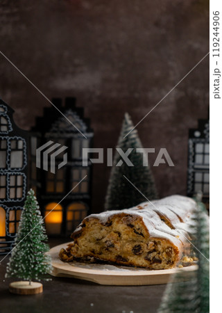 Christmas Stollen in Christmas lights and decoration. Traditional sweet fruit loaf with icing sugar festive pastry dessert. Holiday baking food Christmas Stollen in Christmas lights and decoration. Traditional sweet fruit loaf with icing sugar festive pastry dessert. Holiday baking food 119244906