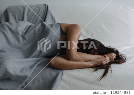 Woman does not want to wake up, using her arms to block the light. 119244981