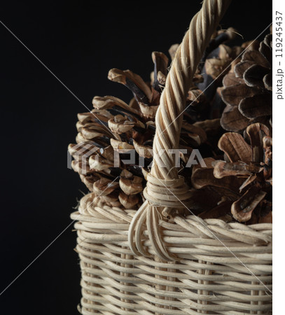 Pine cones in Wicker basket on black background. Pine cones in Wicker basket on black background. 119245437