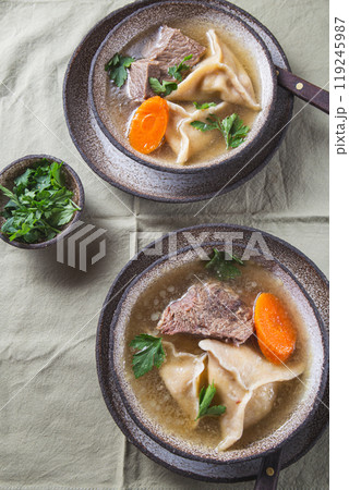 Traditional Jewish Kreplach soup with meat and carrot, gray background Traditional Jewish Kreplach soup with meat and carrot, gray background 119245987