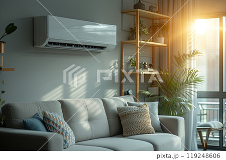 Living room with gray couch and white air conditioner. Apartment is bright and airy, with a large window letting in plenty of natural light 119248606