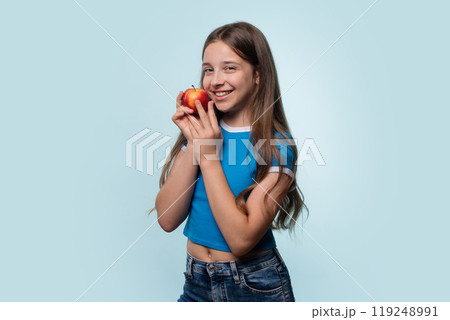 Girl in blue t-shirt smiling while holding red apple 119248991