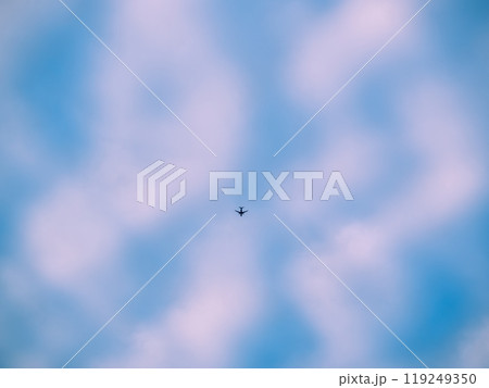 an airplaine fly acrross Beautiful blue evening sky with various fluffy clouds and pink orange sunset an airplaine fly acrross Beautiful blue evening sky with various fluffy clouds and pink orange sunset 119249350