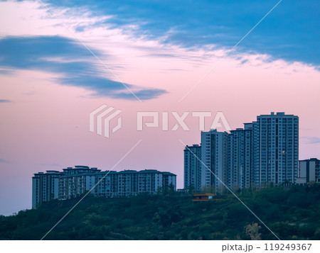 Chongqing city view in sunset, high rise buildings on hills and mountain in the background Chongqing city view in sunset, high rise buildings on hills and mountain in the background 119249367