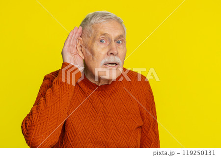 Senior old man trying hear you looking confused and frowning keeping arm near ear for louder voice 119250131
