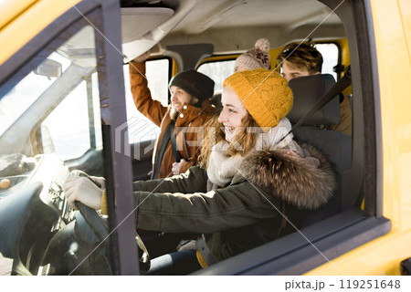 Friends going skiing at ski resort, spending the Christmas holidays together in a cabin. Driving car through a snowy landscape. 119251648