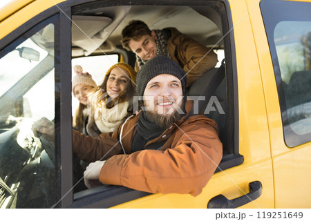 Friends going skiing at ski resort, spending the Christmas holidays together in a cabin. Driving car through a snowy landscape. 119251649
