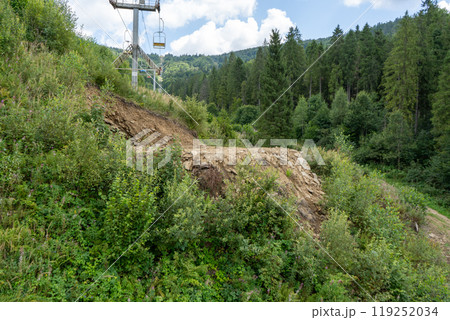 Landslide of soil due to felling of trees in the forest. Carpathians, cable car in nature. 119252034