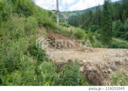 Landslide of soil due to felling of trees in the forest. Carpathians, cable car in nature. 119252045