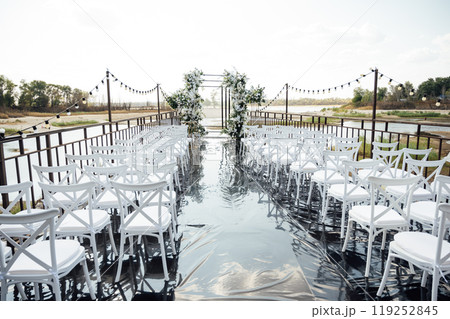 A wedding arch, decorated with flowers, stands on a podium, stands in the open air 119252845
