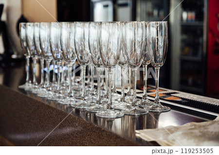 A lot of empty wine glasses. Row of clean glass transparent glasses are on a table on banquet in a bar A lot of empty wine glasses. Row of clean glass transparent glasses are on a table on banquet in a bar 119253505