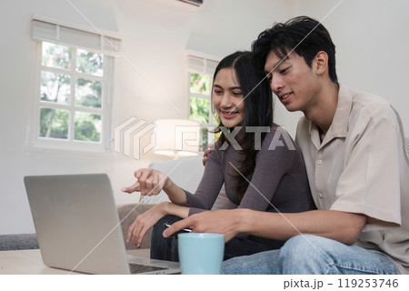 Young Couple Relaxing Together on Sofa, Enjoying Leisure Time at Home with Laptop and Coffee Mug in Cozy Living Room Young Couple Relaxing Together on Sofa, Enjoying Leisure Time at Home with Laptop and Coffee Mug in Cozy Living Room 119253746
