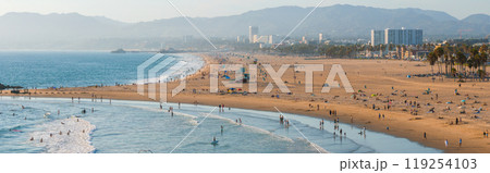 Venice Beach in Los Angeles features a bustling shoreline with people, palm trees, and the distant Santa Monica Pier, set against mountain backdrops. Venice Beach in Los Angeles features a bustling shoreline with people, palm trees, and the distant Santa Monica Pier, set against mountain backdrops. 119254103
