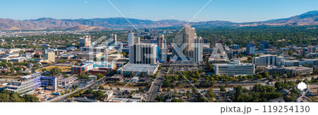 Reno's cityscape features high rise buildings, including Silver Legacy Resort Casino, with the Sierra Nevada mountains and Truckee River in view. 119254130