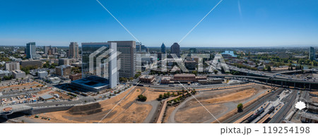 Aerial view of Sacramento, California, featuring a reflective glass building, high rises, highways, and the Sacramento River under a clear blue sky. 119254198