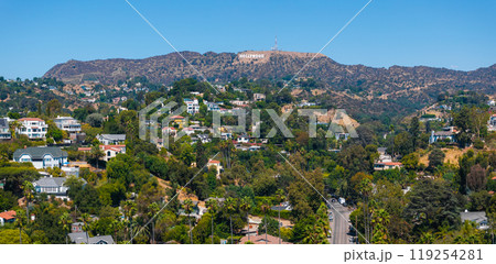 The image captures a panoramic view of Los Angeles' Hollywood district, featuring the Hollywood Sign on the hills and a lush residential area in the foreground. The image captures a panoramic view of Los Angeles' Hollywood district, featuring the Hollywood Sign on the hills and a lush residential area in the foreground. 119254281