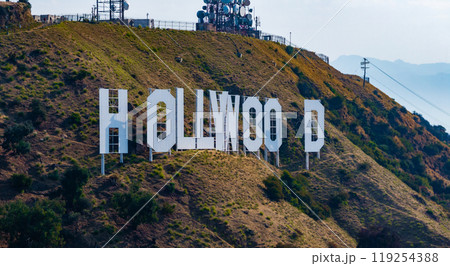 The Hollywood Sign reads 'OLLYWOO' with missing letters, set against rugged hills and sparse vegetation. Communication towers are visible in the background. 119254388