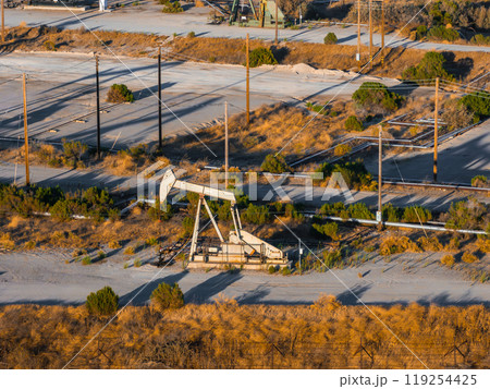 An oil rig stands in a California desert landscape, surrounded by dry grass and shrubs. Utility poles and wires indicate nearby infrastructure. An oil rig stands in a California desert landscape, surrounded by dry grass and shrubs. Utility poles and wires indicate nearby infrastructure. 119254425